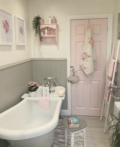 a white bath tub sitting in a bathroom next to a pink door and potted plant