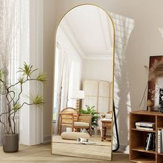 a large mirror sitting on top of a wooden floor next to a book shelf filled with books