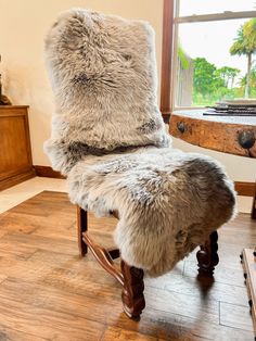 a fur covered chair sitting on top of a hard wood floor next to a window