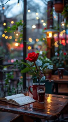 a red rose sitting on top of a wooden table next to a cup of coffee