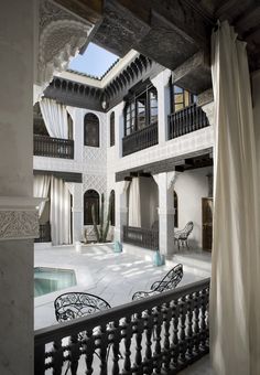 an indoor courtyard with white curtains and black iron railings is seen from the outside