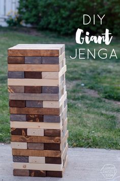 a wooden block tower sitting on top of a cement slab in front of some grass