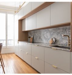 a kitchen with white cabinets and marble counter tops, along with wooden flooring that matches the hardwood floor