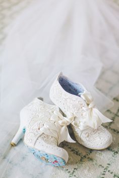 a pair of white shoes sitting on top of a bed next to a wedding veil