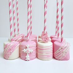 several pink and white cakes with candles in them