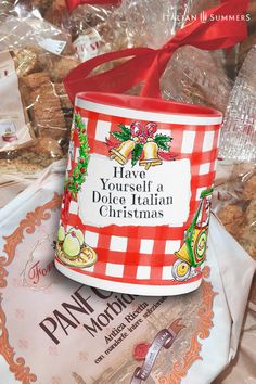 a red and white checkered container with a red ribbon on it sitting next to some cookies