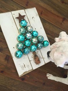 a dog standing next to a christmas tree made out of ornaments