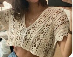 a woman taking a selfie with her cell phone and wearing a crochet top