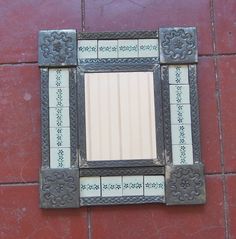 a mirror on the side of a wall with tile around it and an ornate frame