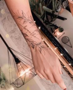 a woman's hand with a tattoo on it and flowers in the middle of her arm