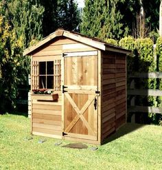 a small wooden shed sitting on top of a lush green field