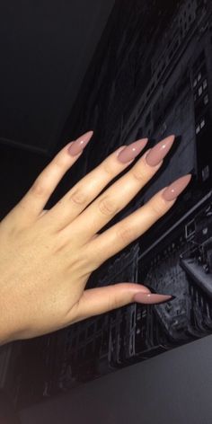 a woman's hand with long, almond - colored nails on the tip of her fingers