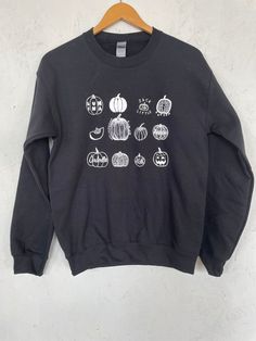 "This listing is for a unisex sweatshirt screen printed with a variety of hand drawn pumpkins. Perfect for halloween! It is shown here printed with white ink on a black sweatshirt. // PROCESS: All of our items are individually hand printed by either me or my dad, which can lead to slight variations in placement. The ink is heat cured and will not fade over time. Since our items are printed to order, there is a 1-2 week processing time before shipping. If you absolutely need an item shipped quick Spooky Black Sweatshirt With Graphic Print, Fall Black Sweatshirt With Custom Print, Fall Black Sweatshirt With Screen Print, Black Screen Print Sweatshirt For Fall, Black Tops With Custom Print For Fall, Black Top With Custom Print For Fall, Custom Print Sweatshirt For Fall Streetwear, Cricut Clothing, Pumpkin Sweatshirt