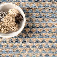 a bowl filled with rubber bands sitting on top of a blue and beige rug next to a white cup