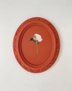 an orange plate with a flower painted on the front and back of it, hanging on a wall