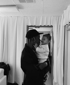 a black and white photo of a man holding a baby in front of a mirror