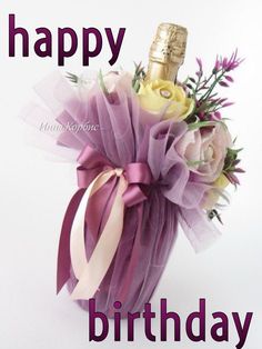 a bottle of champagne and flowers in a purple vase with ribbon tied around the top