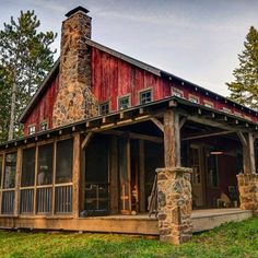 a red cabin with a stone chimney and porch