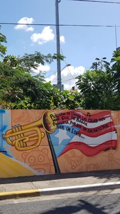 a large mural painted on the side of a building in front of trees and power lines