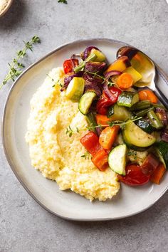 a white plate topped with mashed potatoes and veggies next to a fork