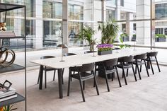 a long table with chairs and plants in it