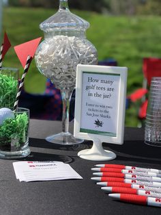 a table topped with vases filled with green plants and golf tees next to a sign that says how many golf tees are in the jar?