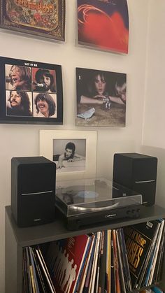 there is a cd player on the shelf in front of some records and pictures hanging on the wall