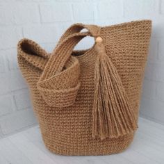 a brown knitted bag sitting on top of a white table next to a brick wall