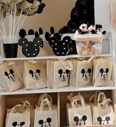 bags with mickey mouse faces on them are sitting in front of some balloons and other decorations