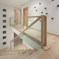 a wooden staircase with glass balustrades and pictures on the wall behind it