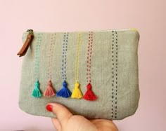 a hand holding a small purse with tassels