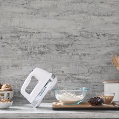 an electric mixer sitting on top of a counter next to bowls and cups filled with food