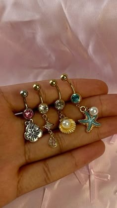 a person is holding five different types of piercings in their hand, including starfish, seahorse, and seashell