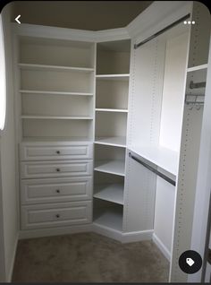 an empty walk in closet with white shelves and drawers