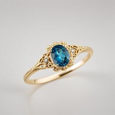 a gold ring with an oval blue stone surrounded by filigrees and diamonds