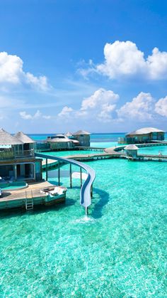 the water is crystal blue and clear with some huts on stilts in the background