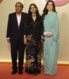 three people standing next to each other on a red carpet