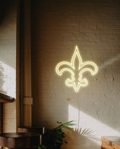 a neon sign that is on the side of a wall in front of a potted plant