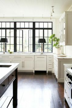 a kitchen with white cabinets and black windows