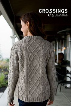 a woman wearing a sweater and jeans is walking down the sidewalk with her back to the camera