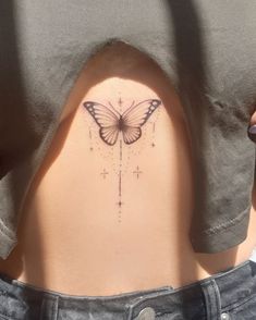 a woman's back with a butterfly tattoo on her lower back and the bottom part of her stomach