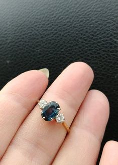 a woman's hand holding a blue and white diamond ring