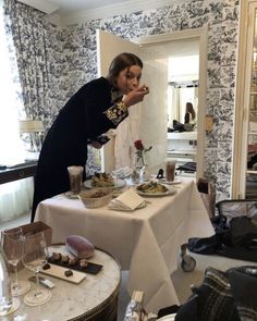 a woman standing in front of a table with food and wine glasses on top of it