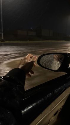 a person's hand sticking out of the window of a car at night time