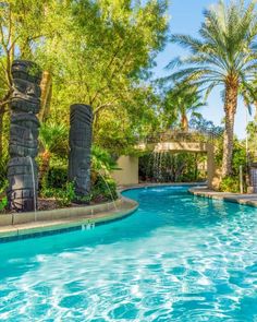 an outdoor swimming pool surrounded by palm trees