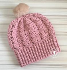 a pink knitted hat with a pom - pom on top