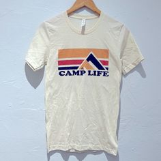 Get Your Camp Of With This Graphic Print Camp Life Tee. Casual Orange Top For Outdoor, Relaxed Fit Camp Shirt With Graphic Print, Relaxed Fit Graphic Print Camp Shirt, Vintage Camp Shirt With Graphic Print, Adventure Graphic Print Crew Neck Camp Shirt, Camping Cotton T-shirt With Screen Print, Camping Life, Graphic Prints, Tee Shirts