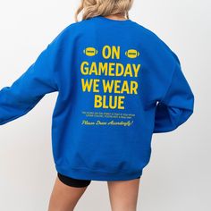 Show your UCLA BRUINS pride with this gameday sweatshirt, perfect for gameday apparel and tailgating outfits. This blue college sports fan gear makes an ideal football fan gift or alumni present, embodying true school spirit for UCLA Bruins supporters. ➡️UCLA BRUINS GAMEDAY FAN SWEATSHIRT:  ✧Features "ON GAMEDAY WE WEAR BLUE"  gold text on front and back. ✧ Sizes range from S -3XL ✧ Heavy Blend cotton and polyester blend crewneck sweatshirt ✧ Relaxed fit, soft feel ✧ No itchy side seams, ribbed Sporty Game Day Sweatshirt With Team Logo, Blue Fan Apparel Sweatshirt With Graphic Print, Blue Graphic Print Fan Apparel Sweatshirt, Game Day Sweatshirt With Team Logo, School Spirit Crew Sweatshirt For Game Day, Blue School Spirit Sweatshirt For Fans, Football Season Game Day Crew Top, Collegiate Crew Top For Game Day, Blue Fan Apparel Sweatshirt For Sports Season