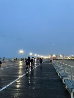 people riding bikes on the boardwalk at night