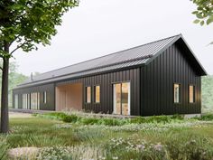 a small black house sitting on top of a lush green field next to tall trees